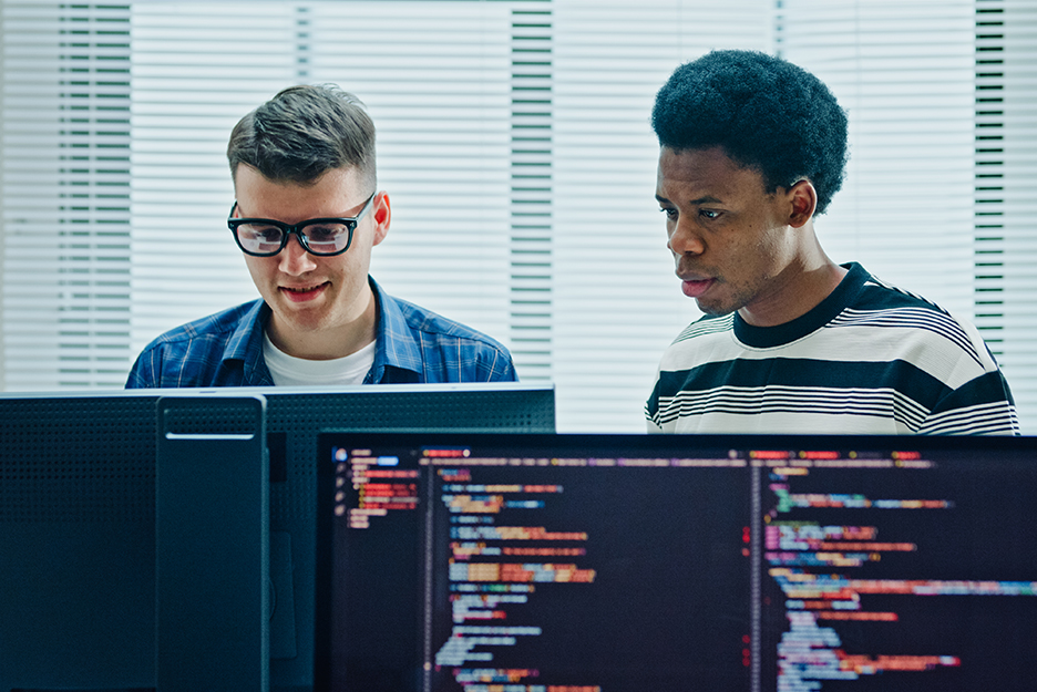 IT-Experten entwickeln und analysieren Cloud-Anwendungen an mehreren Monitoren mit Programmcode.