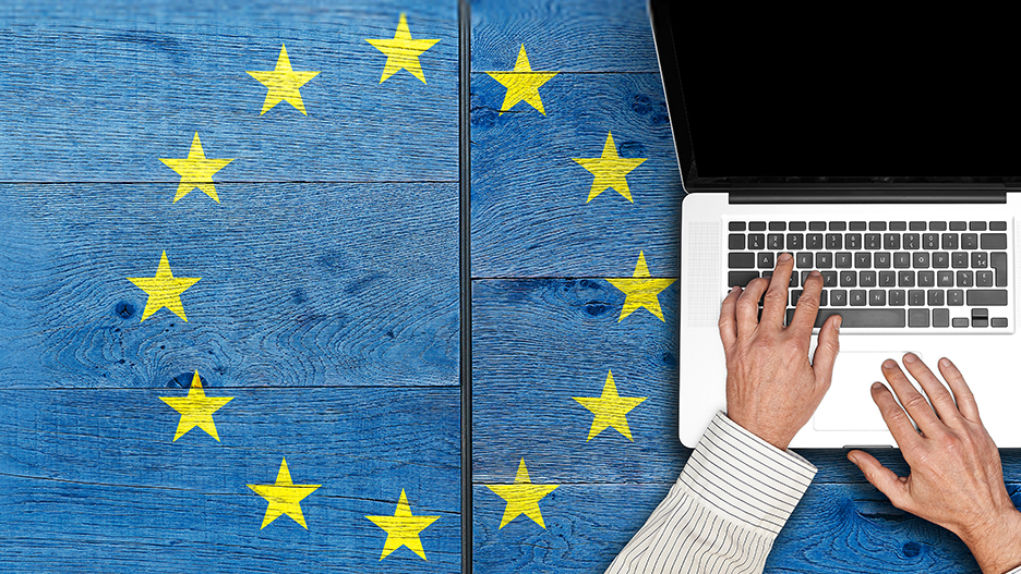 Der EU Data Act in der Praxis Person tippt auf einer Laptop-Tastatur auf einem blauen Holztisch, umgeben von gelben Sternen der EU Flagge