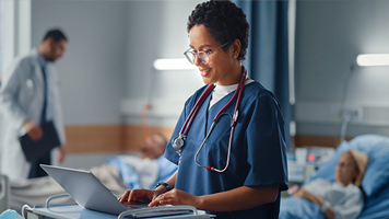 Ärztin unterhält sich mit Patientin und tippt auf Laptop