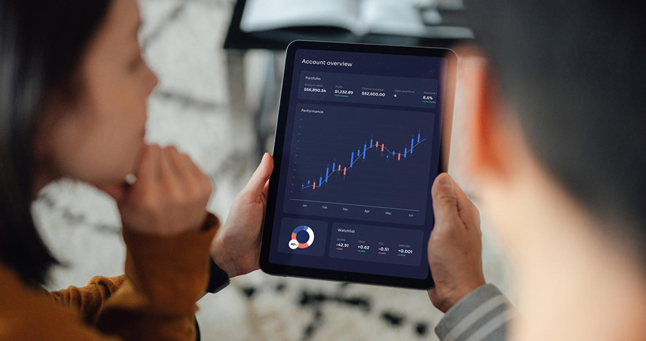 Eine Frau und ein Mann halten gemeinsam ein Tablet auf dem eine Grafik zu sehen ist 